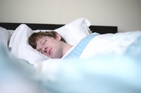A young man sleeping in his bed.
