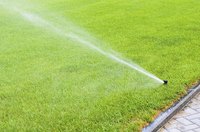 A sprinkler irrigating a green lawn with water.