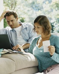 A married couple pay bills together in their living room.