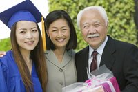 Parents receiving a gift from their daughter in a graduation gown.