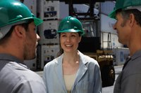 Men and women on a jobsite are wearing safety helmets.