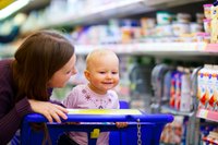 A woman affectionately talking to her baby while grocery shopping.