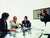 Three people are being interviewed at a press conference.