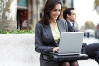 A businesswoman is typing outside.