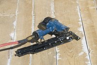 Nail gun laying on wooden floor.