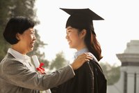 A mother stands with her daughter at her college graduation ceremony.