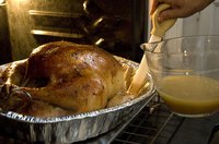 Woman using a baster to glaze a turkey in the oven.