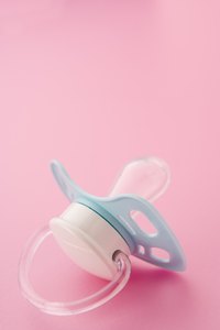 Integrate a pacifier with a looped handle into the mom-to-be's corsage.