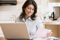 Woman on laptop looking at a paper