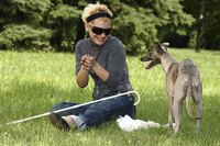A blind woman is playing with her dog.