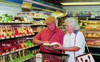 A couple is grocery shopping and reading labels.