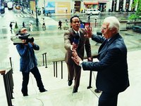 A man is trying to walk away from reporters.