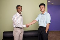 Two businessmen shaking hands in an office lobby.