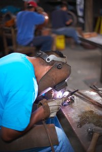 Assemble angle-iron tables with an arc welder.