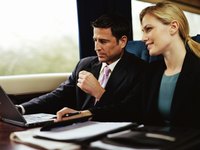 A businessman and woman are at work on their commute.