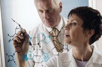 Scientists drawing chemical diagrams on glass.