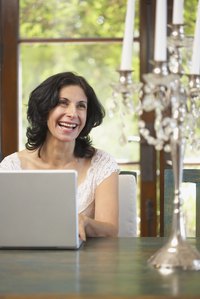 A woman is using her laptop in her table.