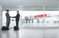 Two businessmen shaking hands on agreement in airport.