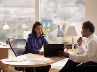 A manager and employee having a discussion at an office desk.