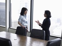 Two businesswomen talking in a conference room.