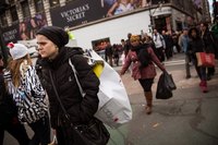 Consumers carrying shopping bags in a city square.