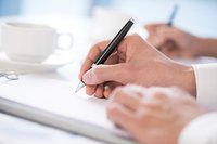Close-up of hands writing in notebooks