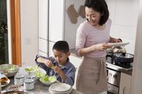 An Asian mother and son prepare a meal in their kitchen