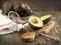 An avocado cut in half on a cutting board.