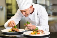 A chef plates a dish in a restaurant kitchen.