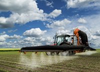 A tractor sprays pesticide on a soybean field