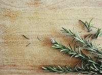 A sprig of freshly cut rosemary on a cutting board.