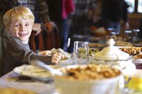 A young boy standing next to a Thanksgiving feast on a table.