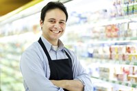 A grocery store worker standing in front of stocked shelves.