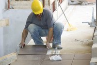 A builder laying tile on a construction site.