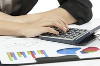 Close-up of hands working a calculator next to financial documents