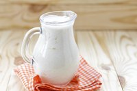 A glass pitcher of cultured buttermilk on a gingham towel.