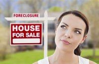 Woman in front of foreclosure house for sale sign