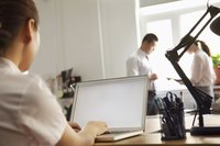 Man writing up business narrative on laptop in office.