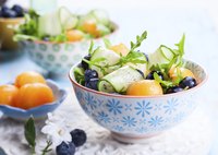 A bowl of cucumber, cantelope and blueberry salad.
