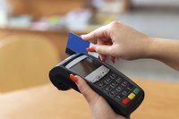 A woman swiping a debit card at a store counter.