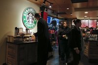 The Starbucks logo illuminating on the wall behind the retail counter.