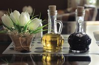A bottle of olive oil and red wine vinegar on a kitchen counter.