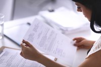 A businesswoman reading a document at her desk.