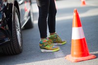 A woman crossing the street wearing Nike high tops.