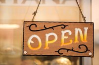 A close-up of an open sign with western accents on a retail shop door.