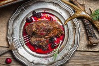 A plate of venison with cranberry sauce.