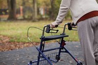 An elderly woman uses a walker.