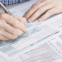 Close-up of a man filling out tax forms with a pen.