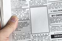 Looking through newspaper advertisements.