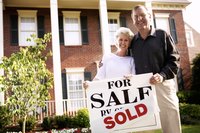 Adult couple standing in front of their home that has just been sold